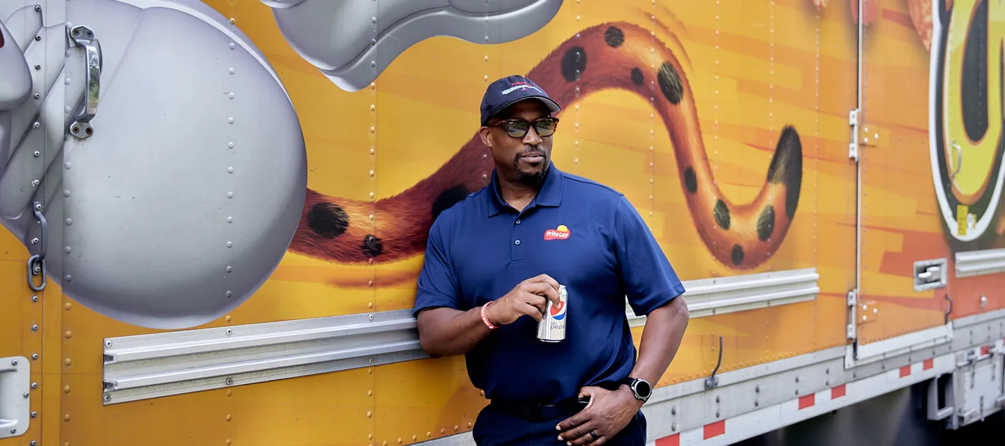 Man standing in front of semi truck drinking a Pepsi